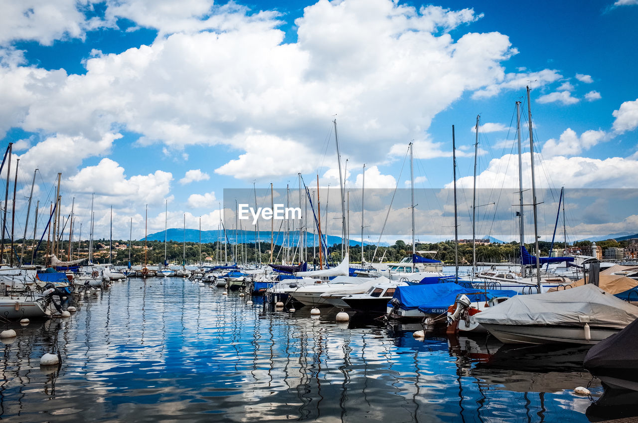 Scenic view of boats moored in water against cloudy sky