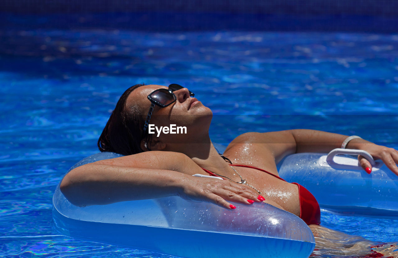 Woman with inflatable raft swimming in pool during summer