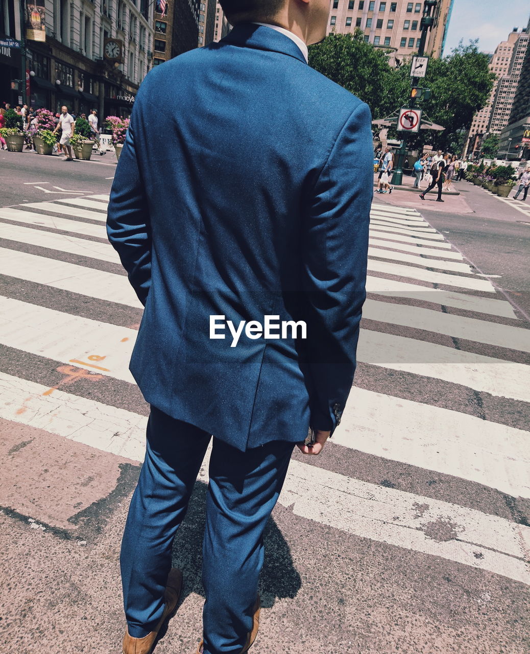 Rear view of businessman standing on zebra crossing in city during sunny day