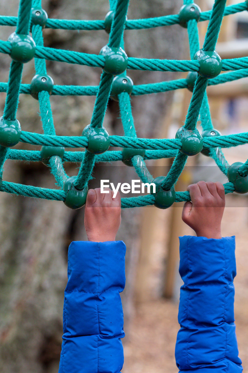 Cropped hands of child hanging on rope