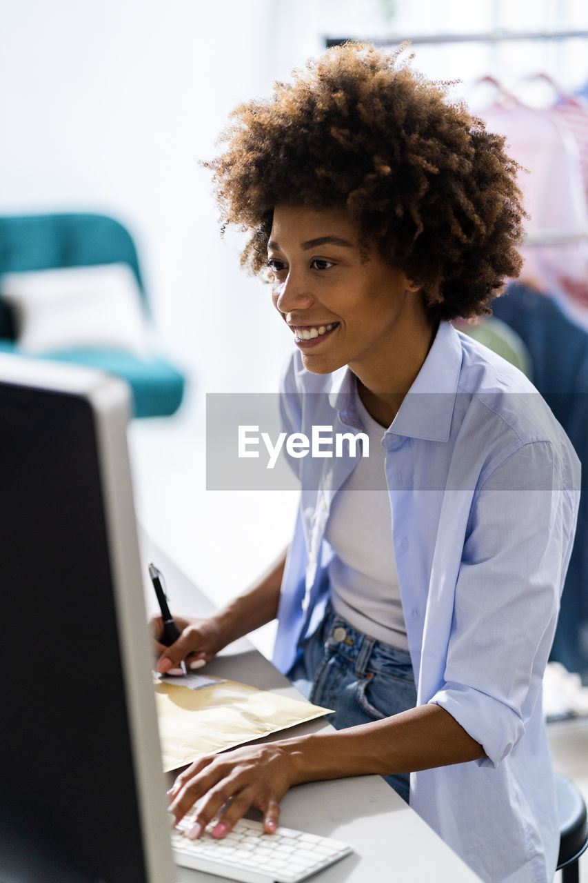 Smiling female entrepreneur using desktop computer while working at studio