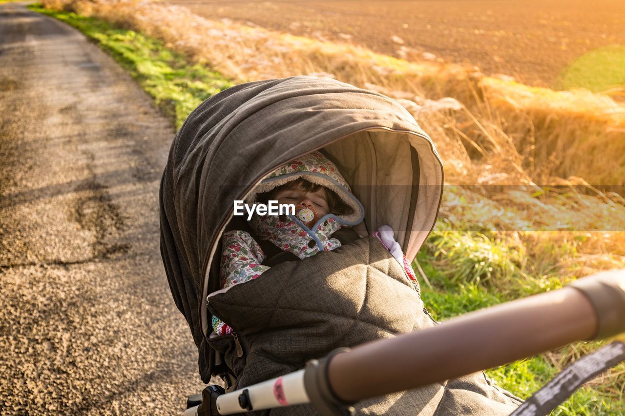 High angle view of baby sleeping in stroller on road by field