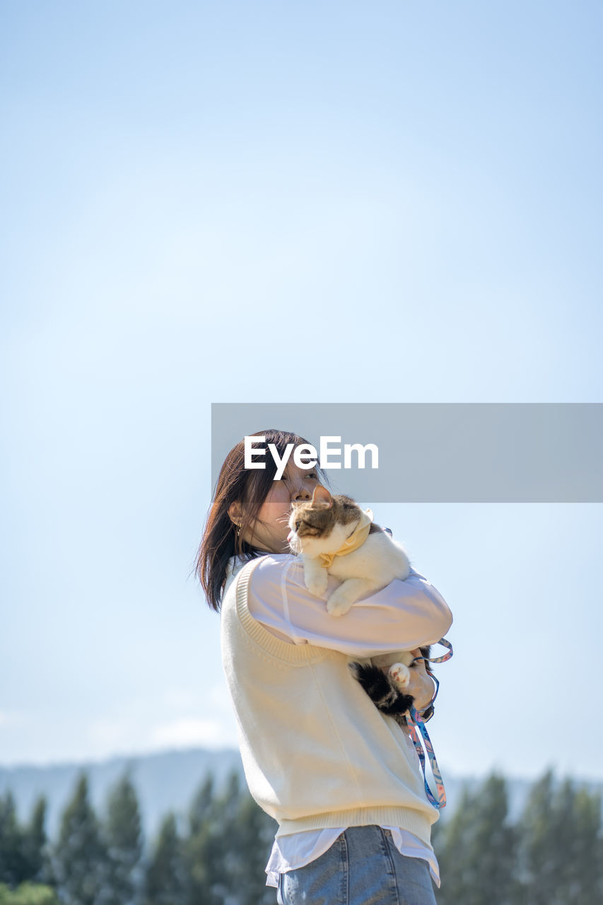 Woman embracing cat outdoors