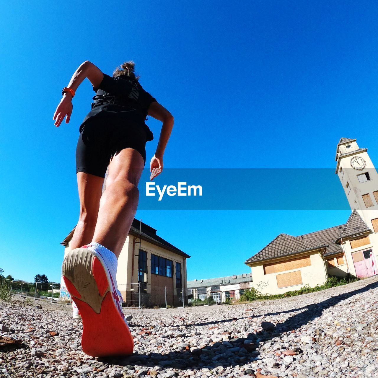 Low section of woman standing against clear blue sky