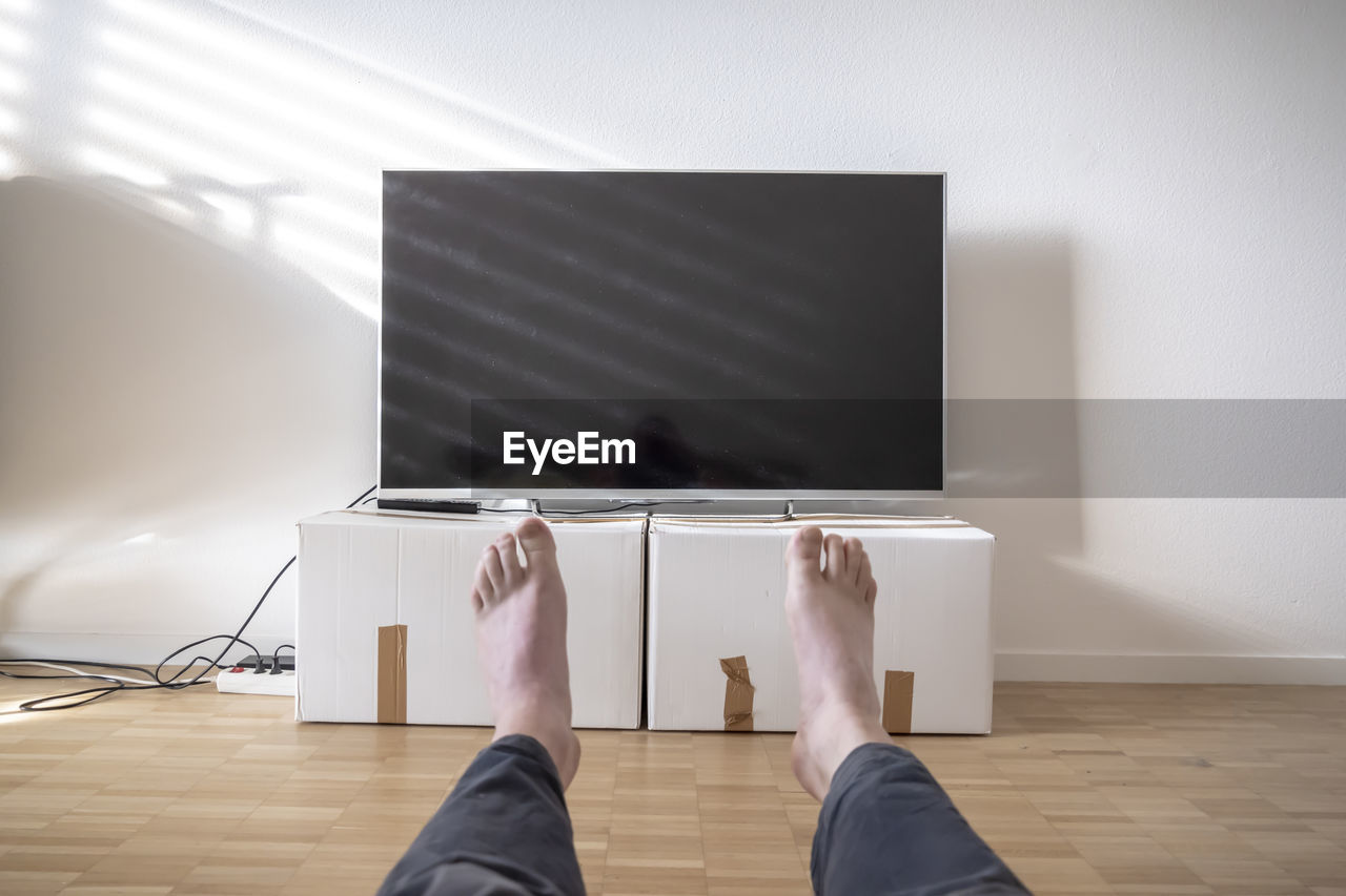 Television on cardboard box in living room and men legs in switzerland.