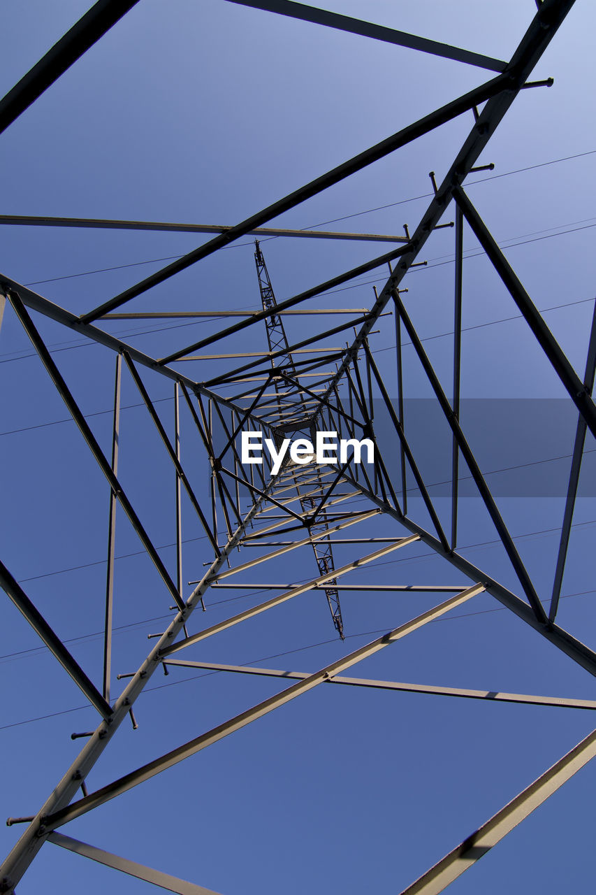 Directly below shot of electricity pylons against clear blue sky