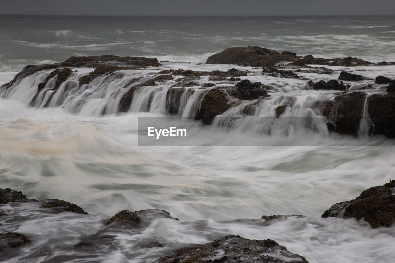 SCENIC VIEW OF SEA AGAINST ROCKS IN SKY