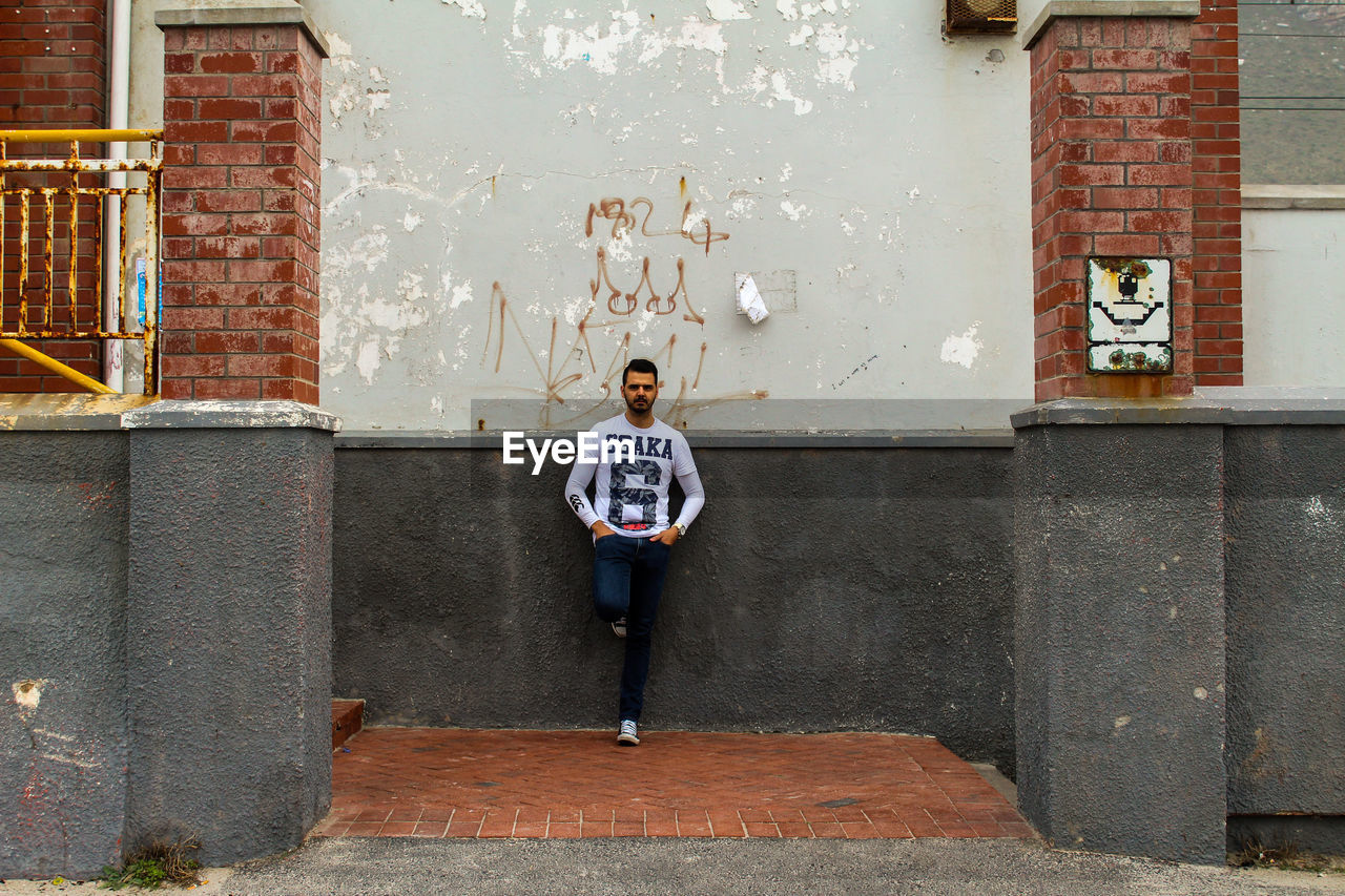 FULL LENGTH OF BOY STANDING AGAINST WALL