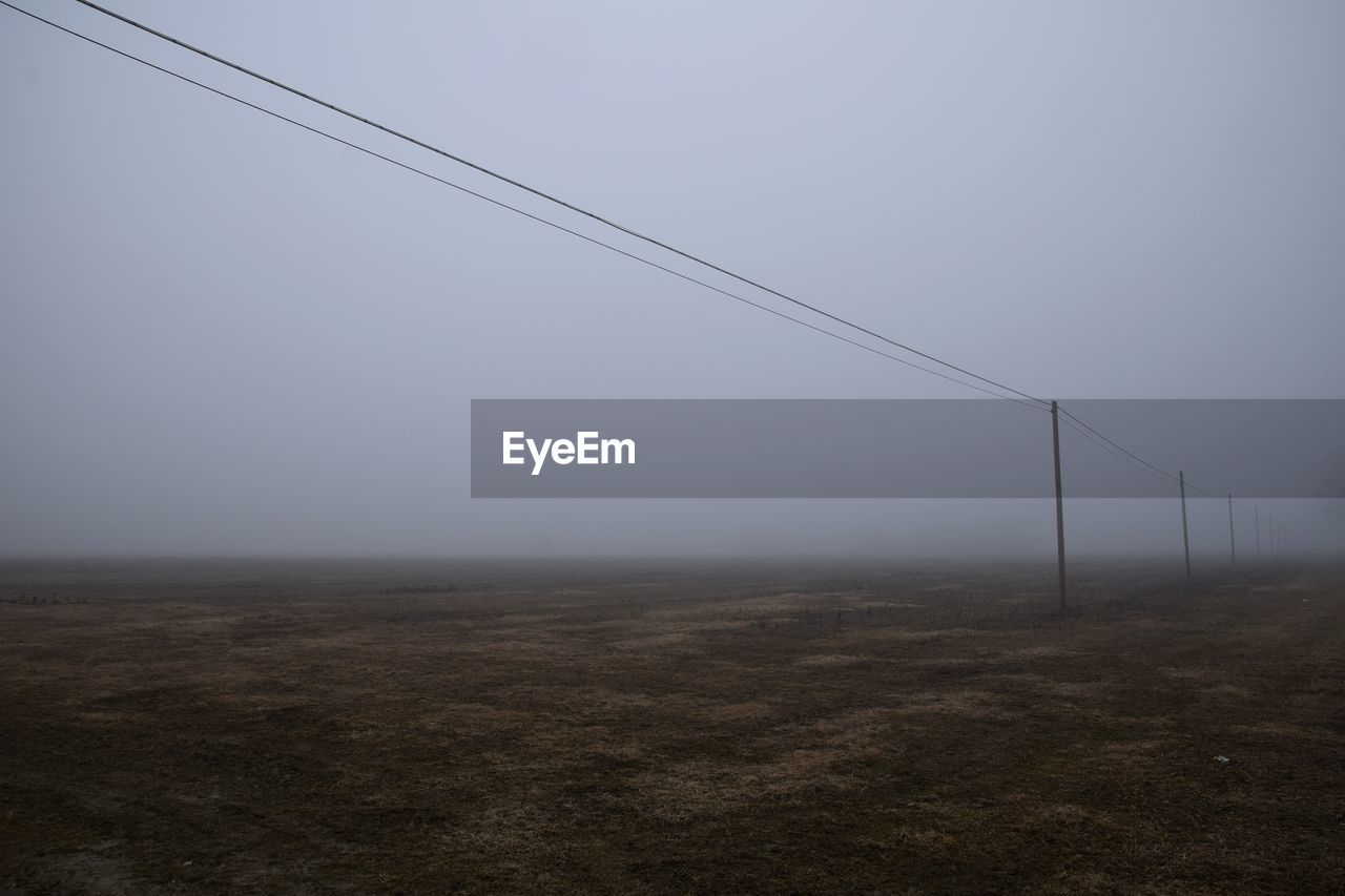 fog, horizon, environment, sky, wind, line, nature, landscape, no people, cable, copy space, morning, land, haze, tranquility, electricity, day, beauty in nature, outdoors, scenics - nature, mist, technology, tranquil scene, light, non-urban scene, field, remote