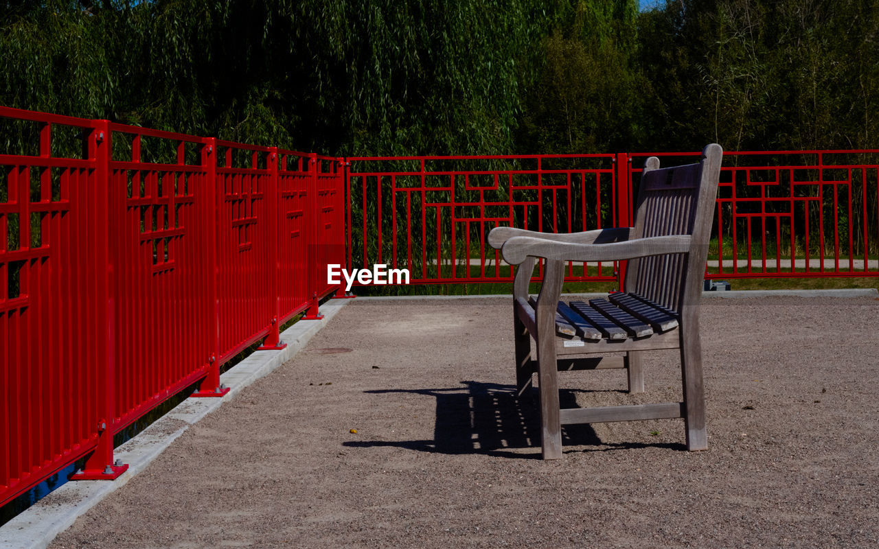Empty wooden bench in the park surrounded by red railing