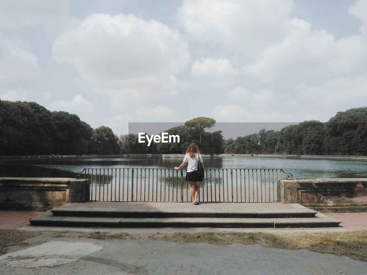 Rear view of woman standing by pond