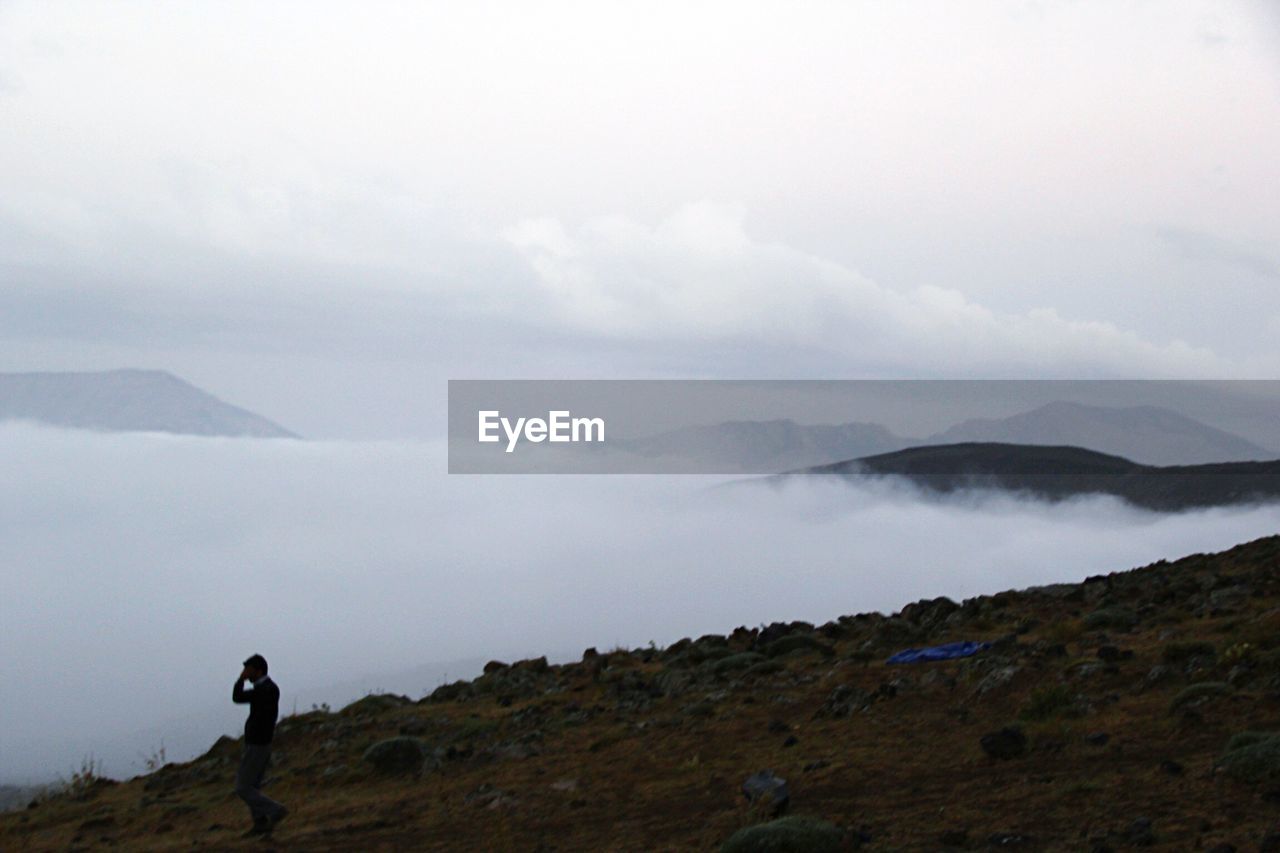 WOMAN STANDING ON MOUNTAIN LANDSCAPE