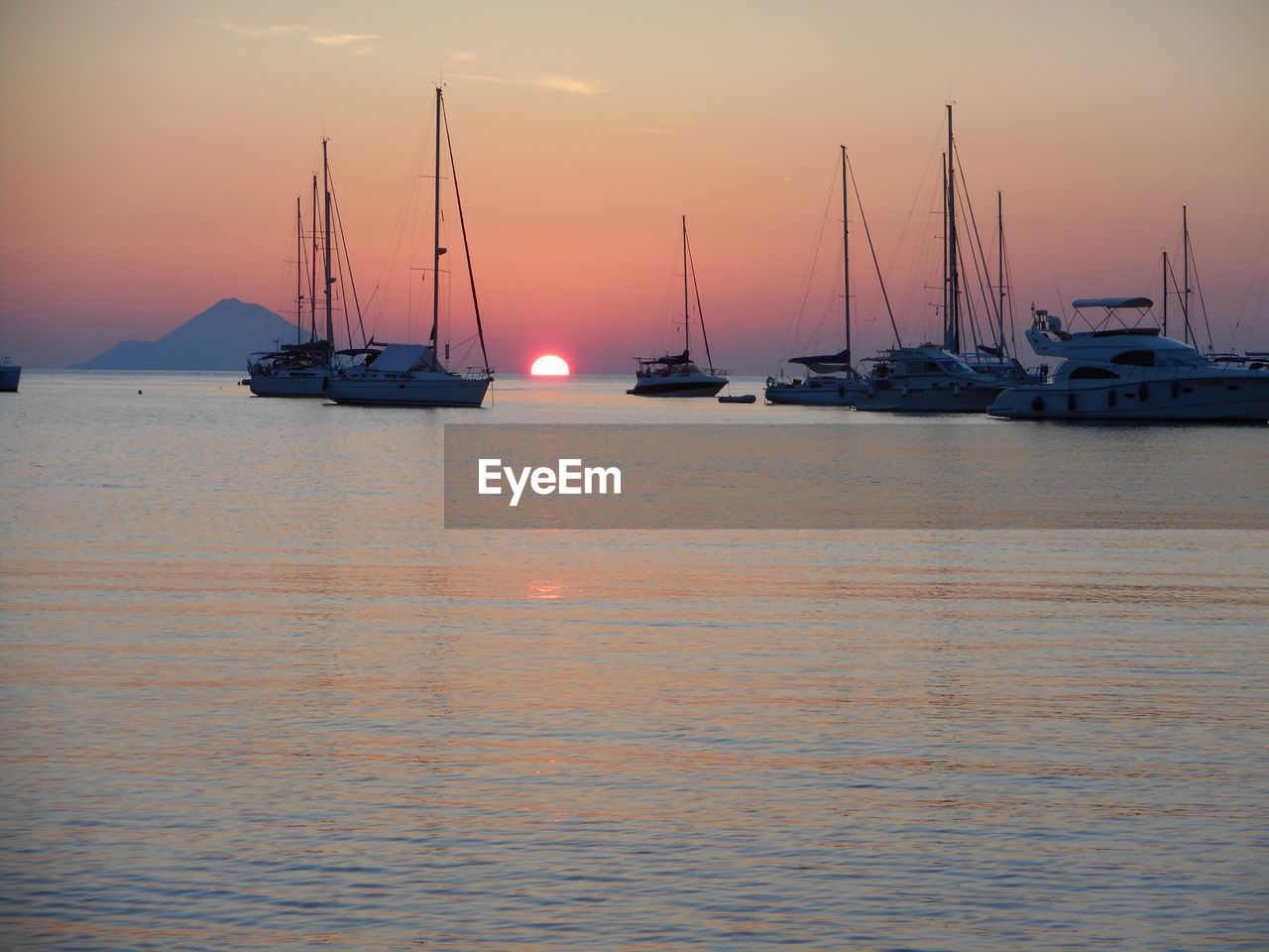 SAILBOATS IN SEA AT SUNSET