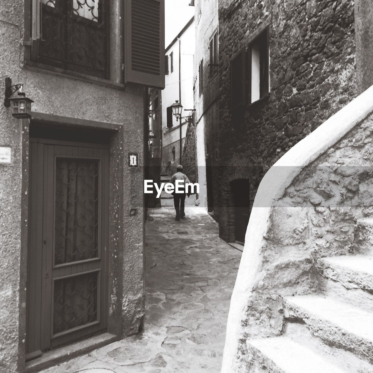 REAR VIEW OF MAN WALKING ON STEPS OUTSIDE HOUSE