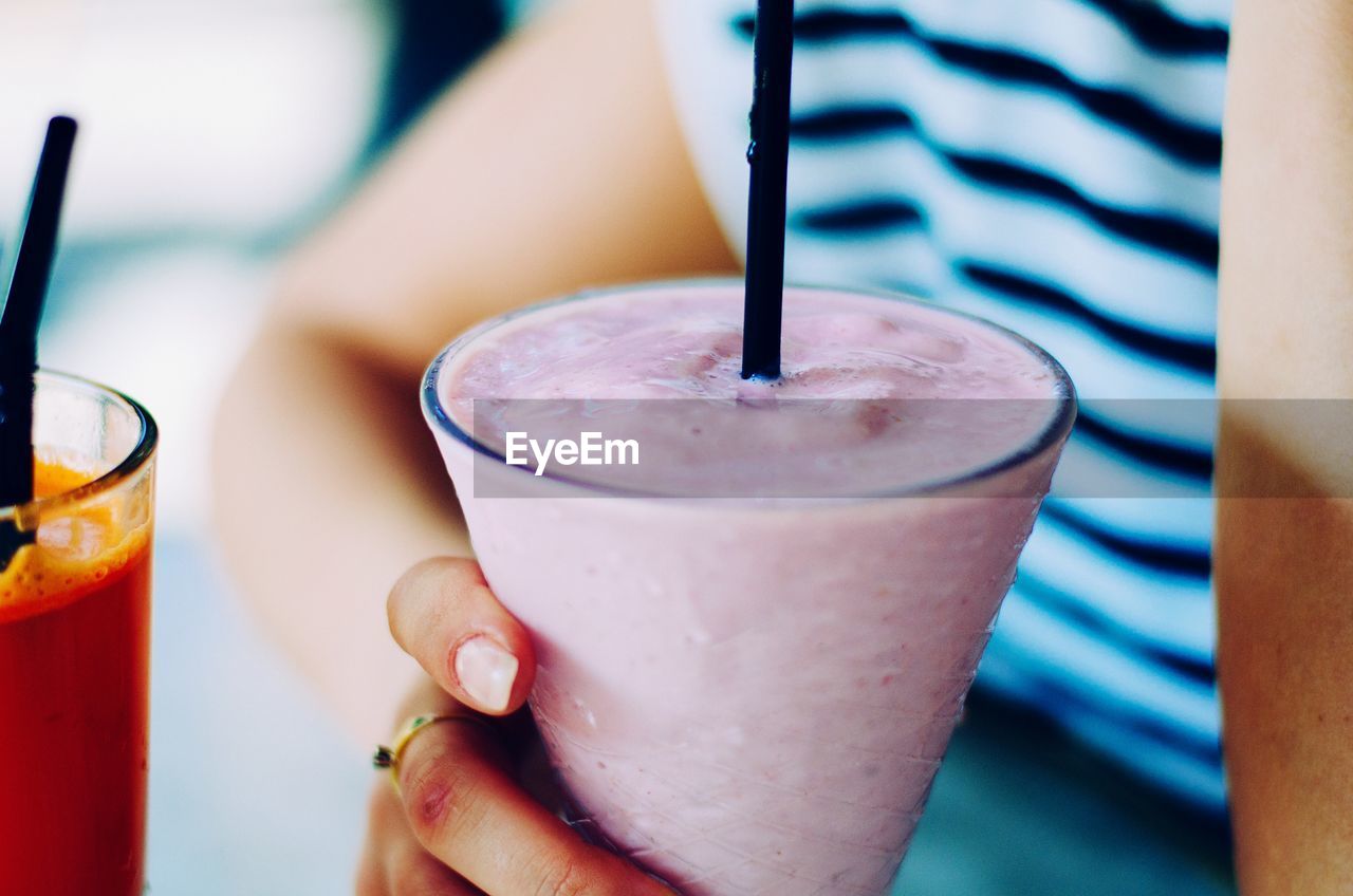 Cropped image of woman holding glass of strawberry smoothie