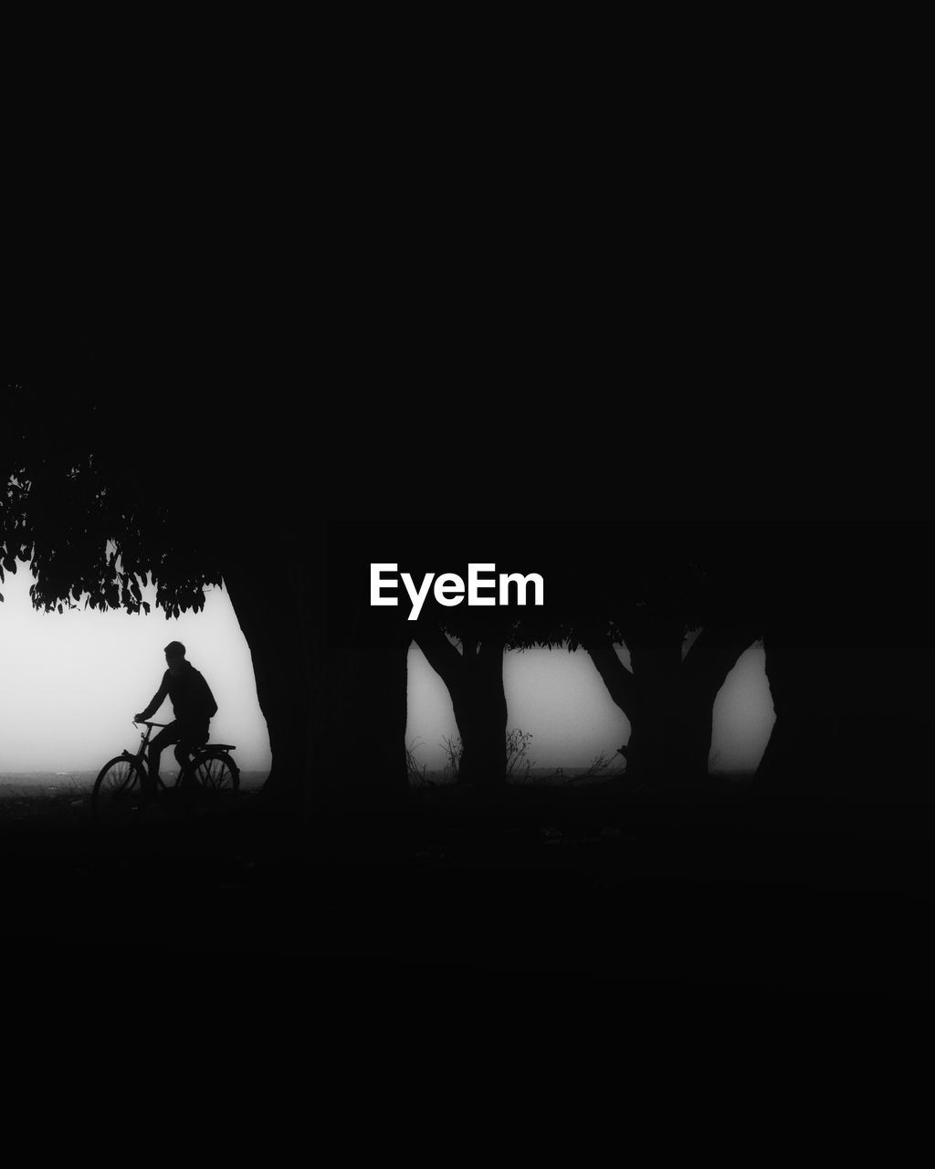 Silhouette of man riding bike during a winter morning