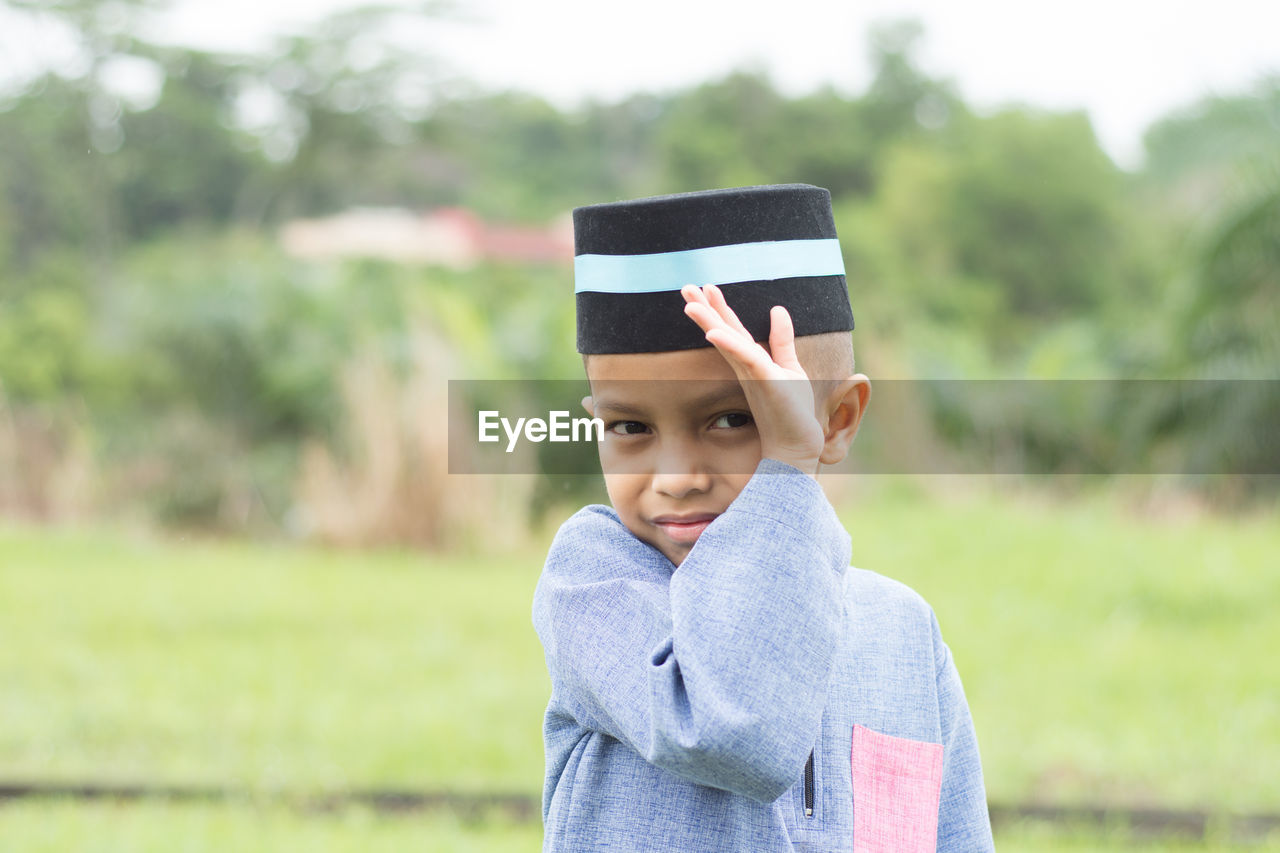 Close-up of boy standing against trees