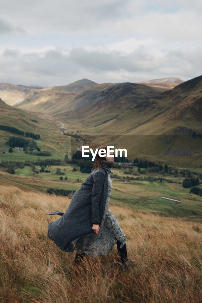 Woman walking on field against mountains