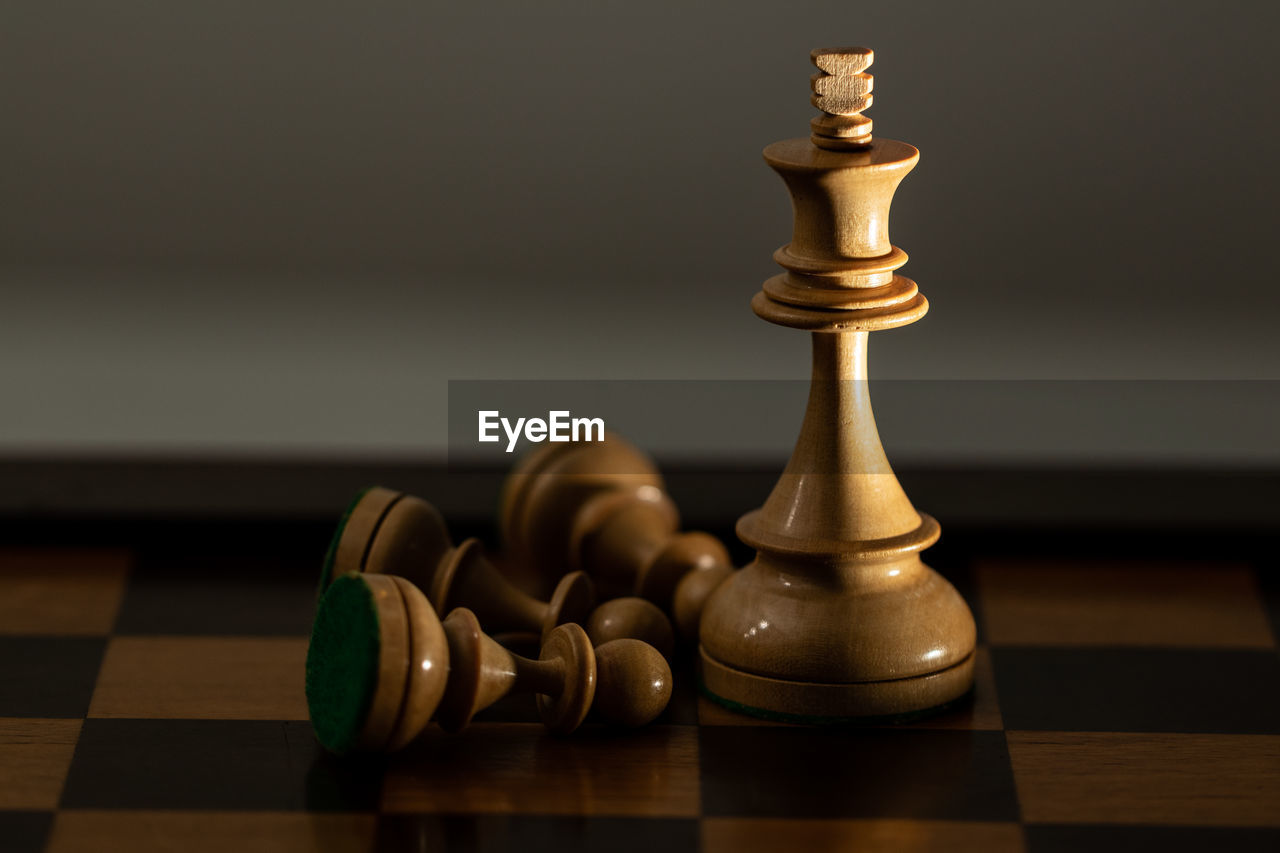 Close-up of game pieces on chess board against brown background