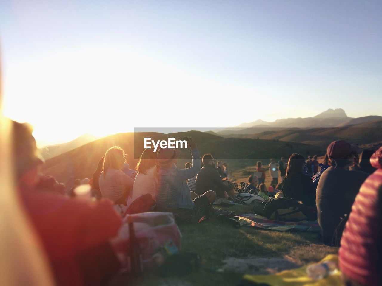 Group of people on mountain against sky during sunset