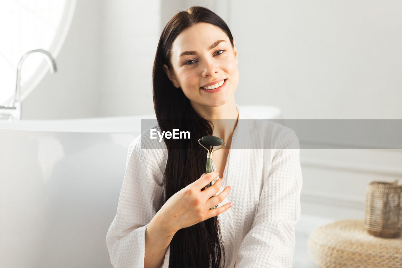 portrait of young woman using mobile phone while sitting at home