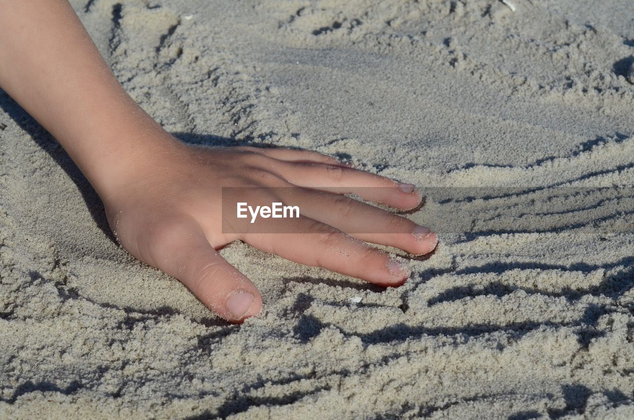 sand, land, beach, one person, human leg, barefoot, hand, high angle view, soil, nature, limb, day, leisure activity, lifestyles, low section, close-up, vacation, sunlight, childhood, women, trip, outdoors, human foot, child, holiday