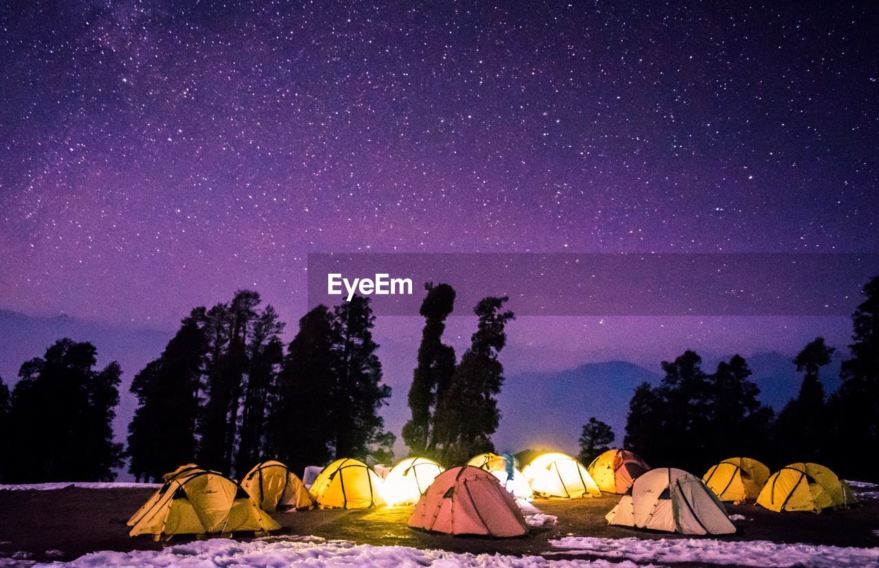 Scenic view of himalayan mountains with illuminated tends  against stars in the sky at night