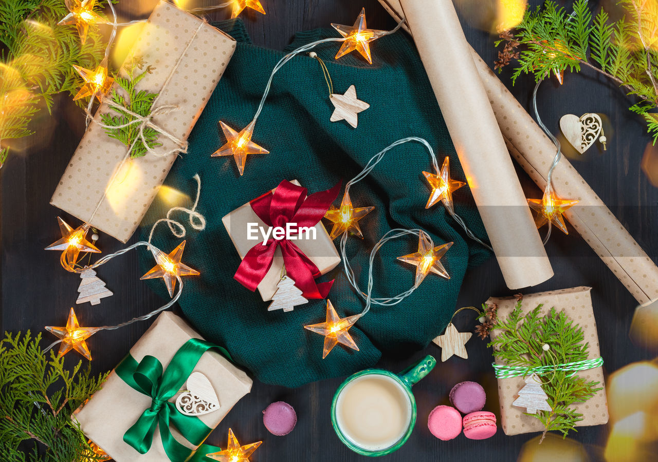 Christmas composition with gifts, garland lights and decorations on a dark wooden background.