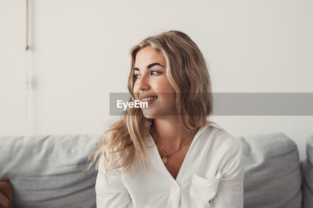 adult, women, indoors, one person, smiling, furniture, person, happiness, emotion, sitting, portrait, looking, portrait photography, female, sofa, long hair, business, lifestyles, clothing, domestic room, conversation, relaxation, young adult, human face, hairstyle, casual clothing, front view, home interior, businesswoman, domestic life, copy space, positive emotion, brown hair, contemplation, photo shoot, cheerful, looking away, headshot, living room, blond hair, business finance and industry, enjoyment