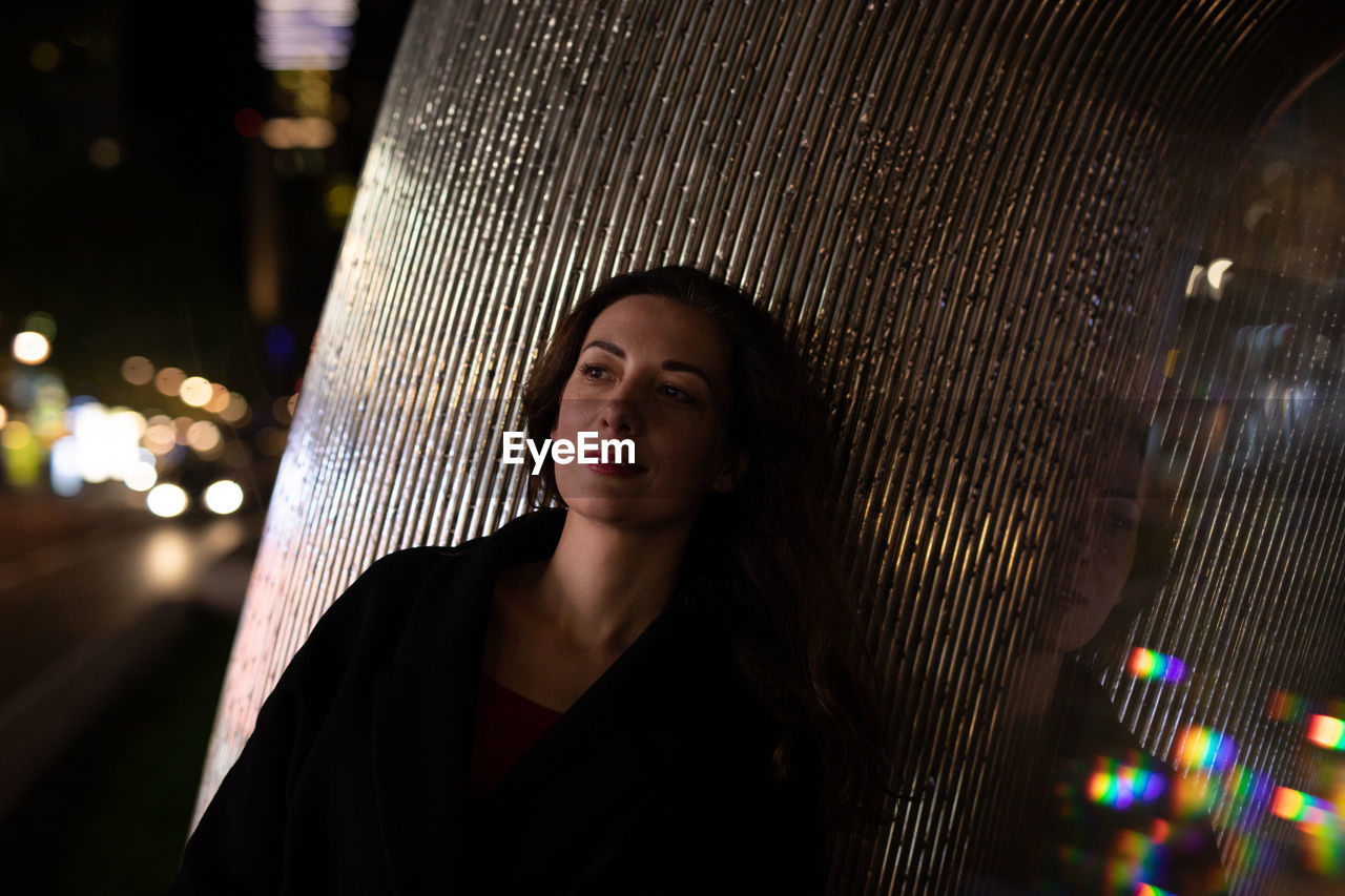 Mid adult woman leaning on pillar in city