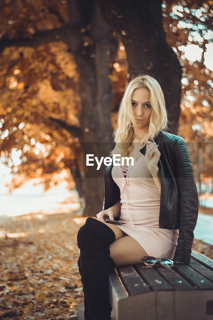 Portrait of young woman sitting on bench at park