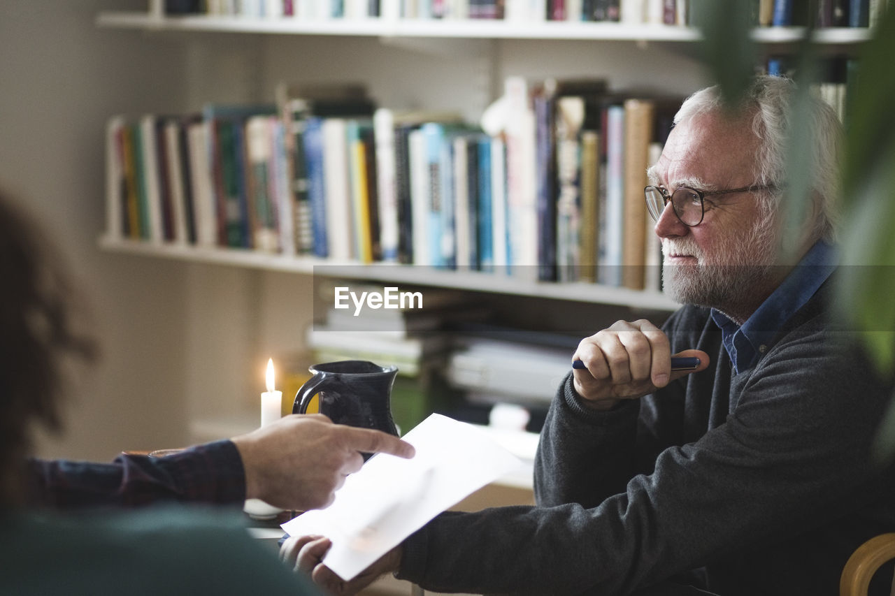 Therapist discussing over document with mature couple at home office