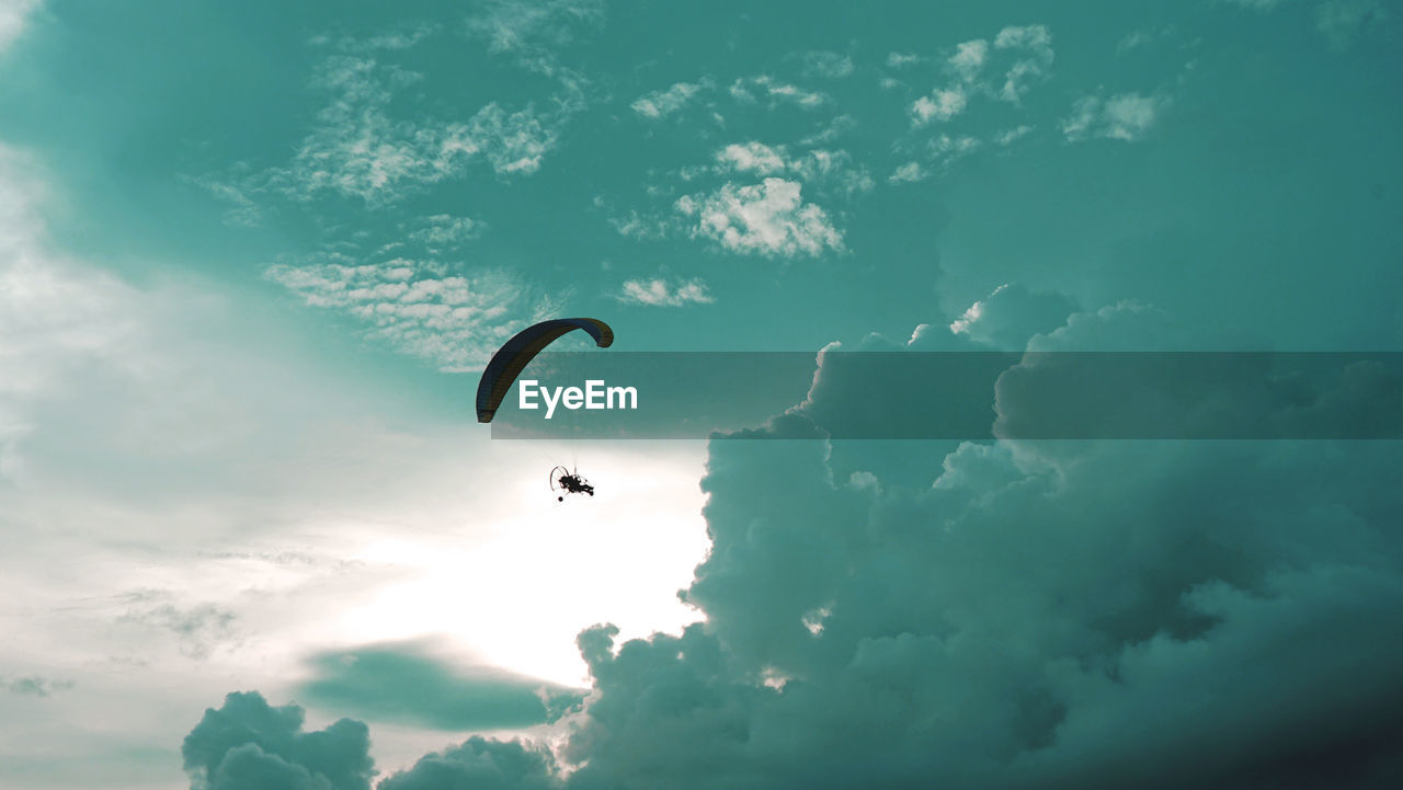 Low angle view of person paragliding against sky