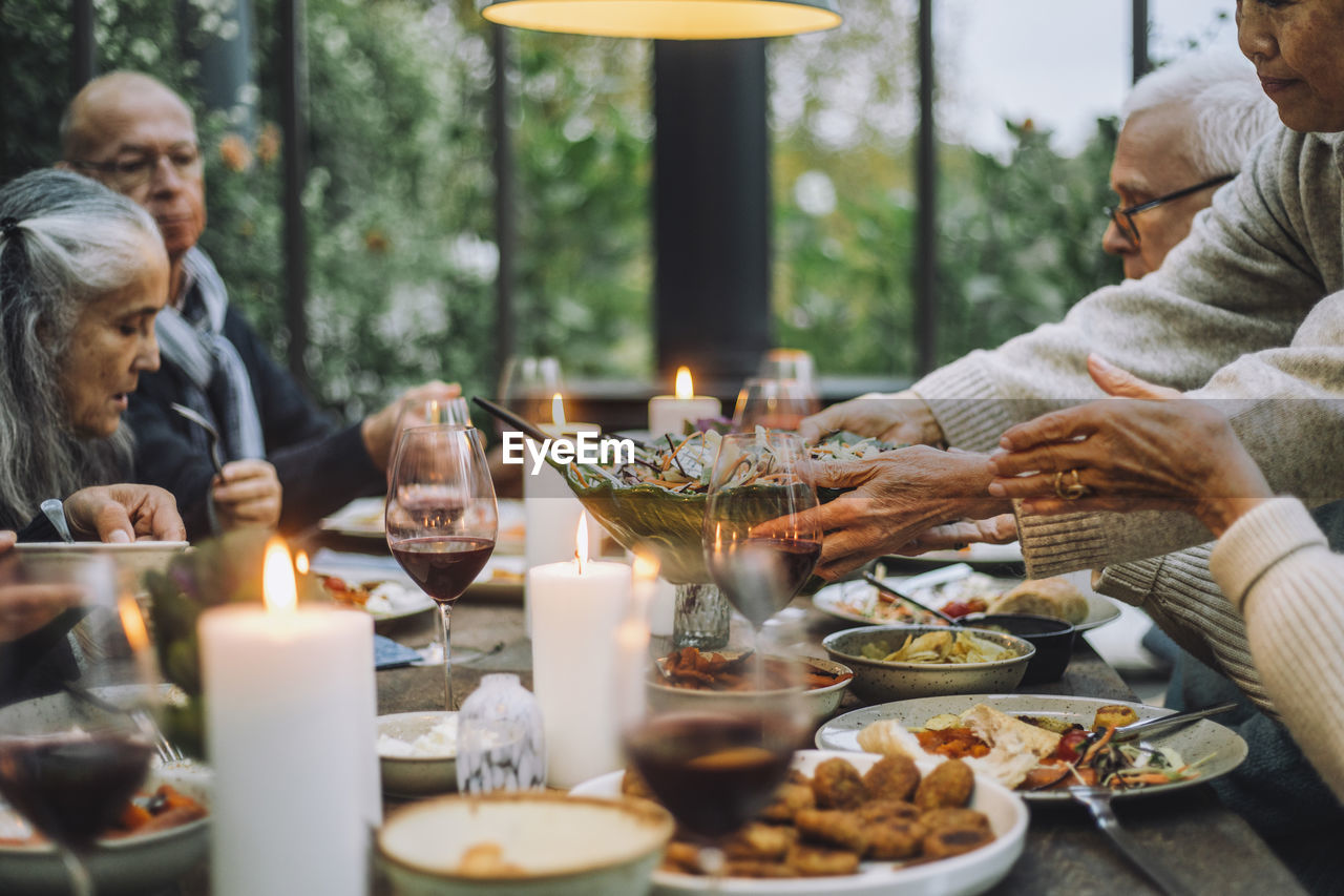 Senior woman serving salad to male and female friends during party