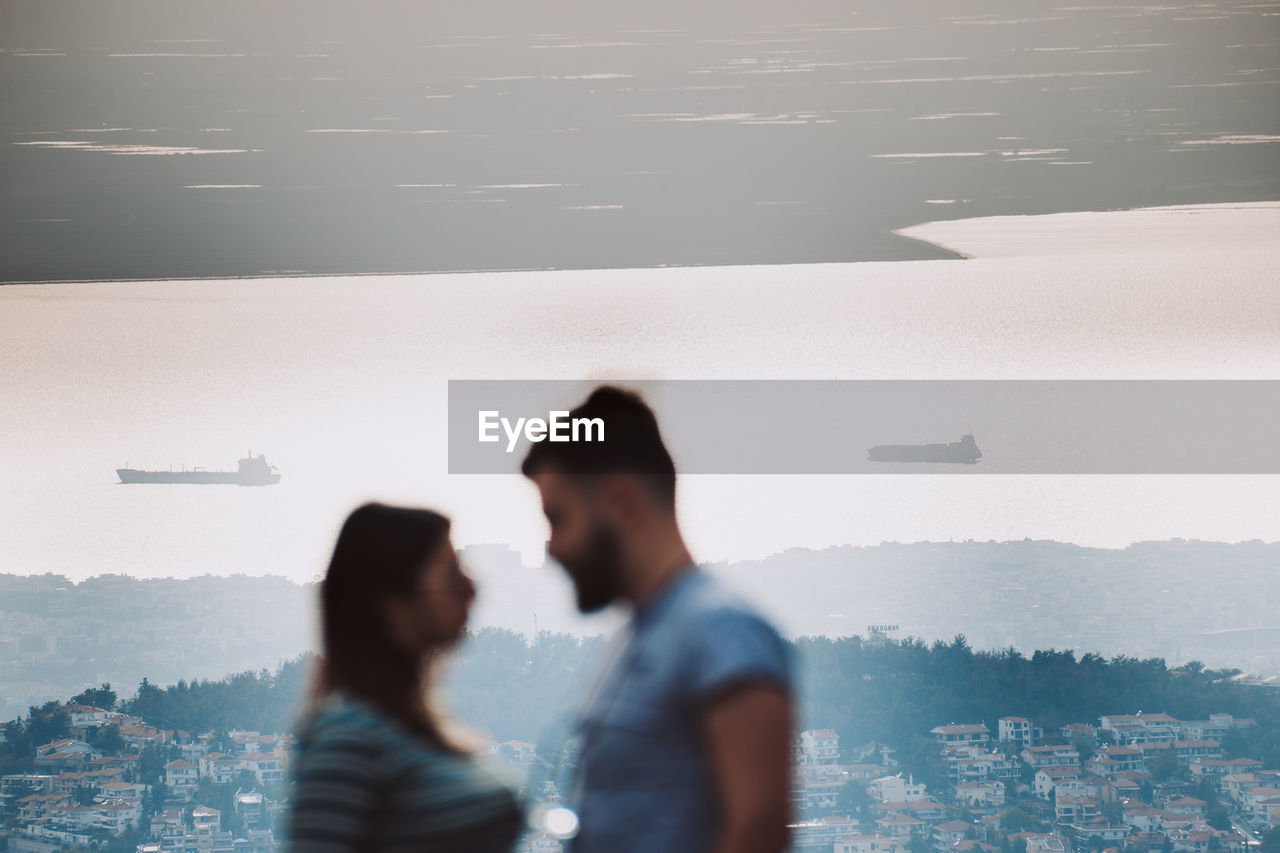 People standing by cityscape in city against sky