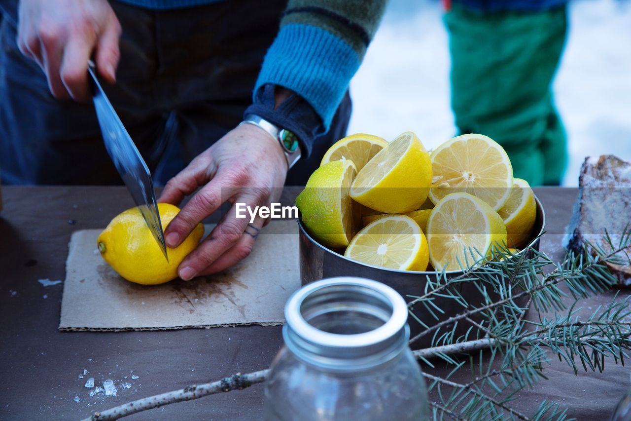 Cropped image of man cutting lemon at table