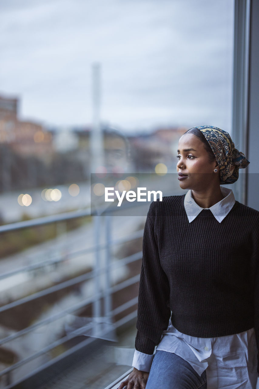 Young woman looking through window