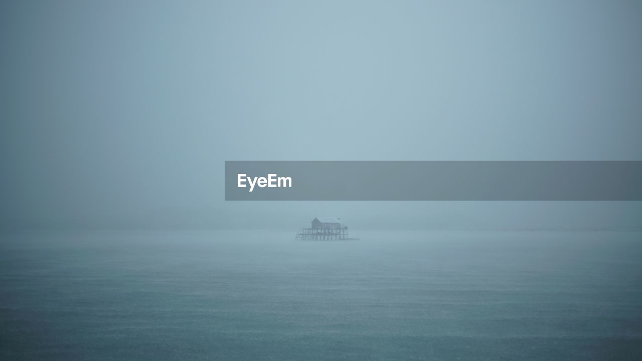 Boat sailing in sea against sky during foggy weather