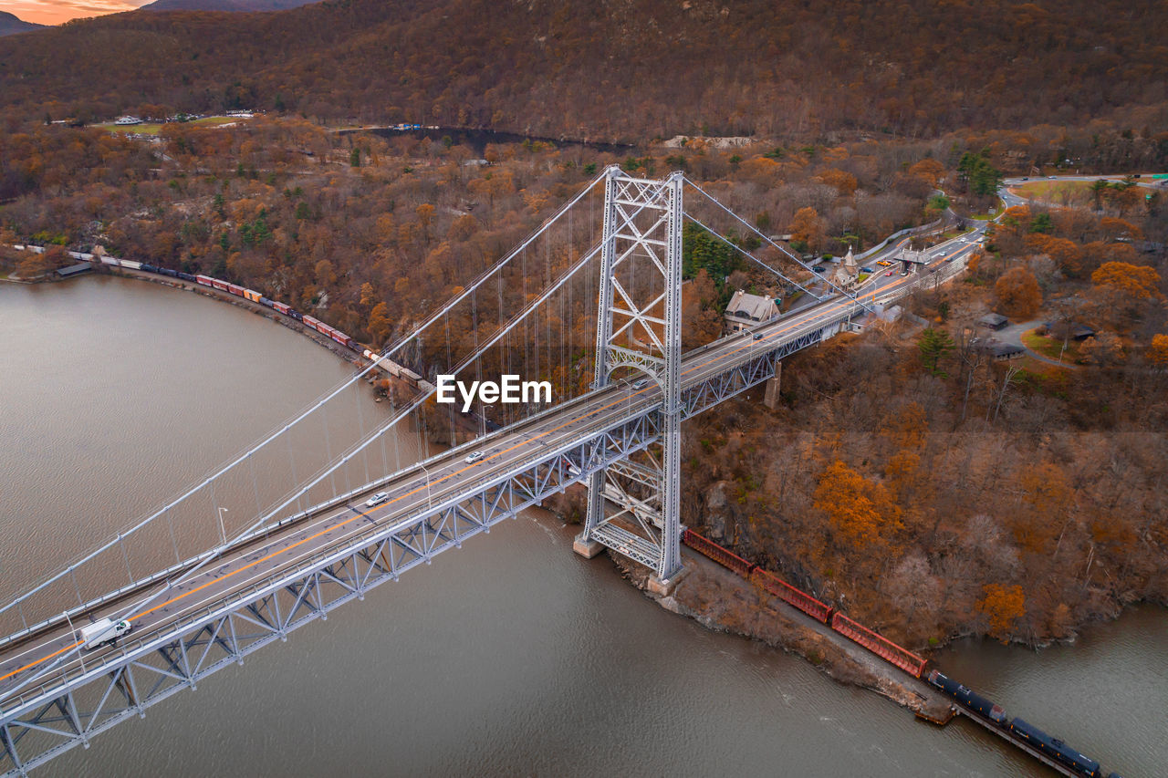 HIGH ANGLE VIEW OF SUSPENSION BRIDGE OVER RIVER AGAINST SKY