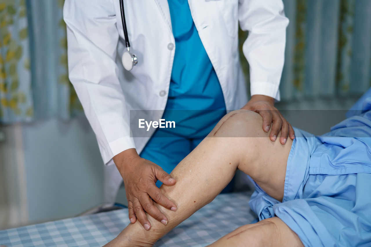 Midsection of doctor checking patient with knee surgery