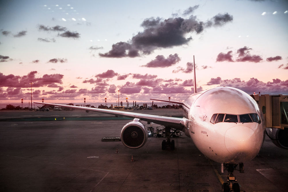 Airplane in airport against sky during dusk