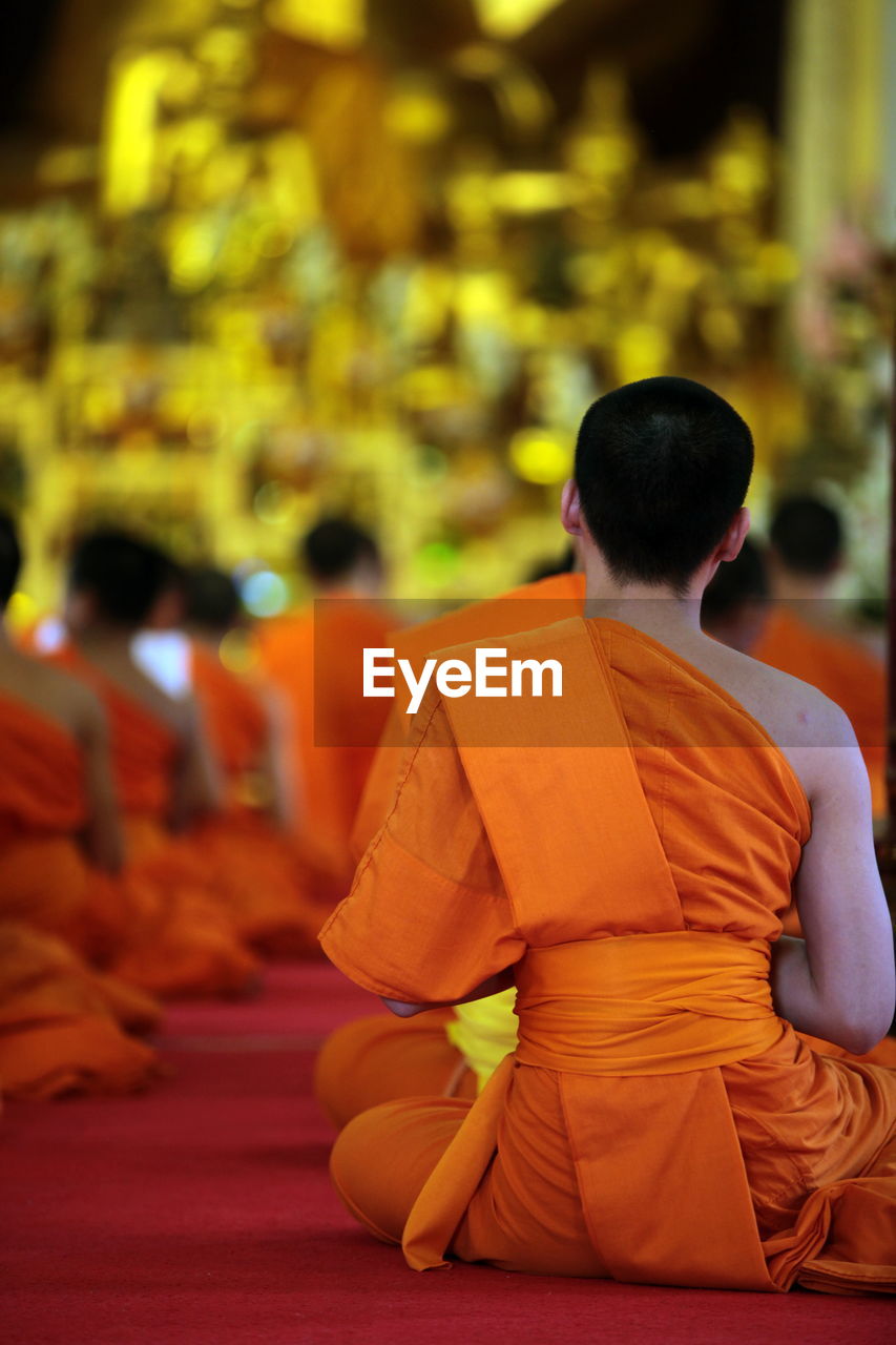 Rear view of monks sitting at temple