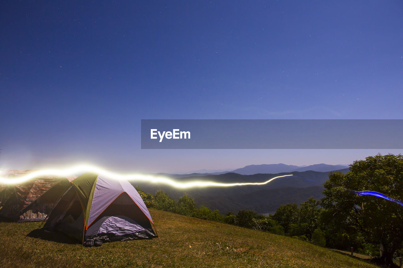 TENT AGAINST MOUNTAIN RANGE AT NIGHT