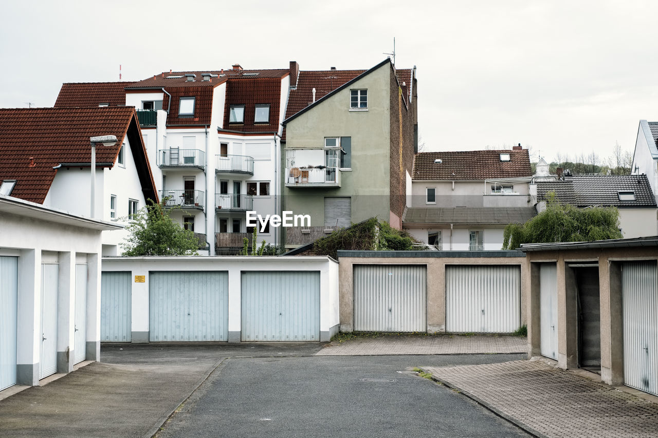 Residential buildings by street against sky