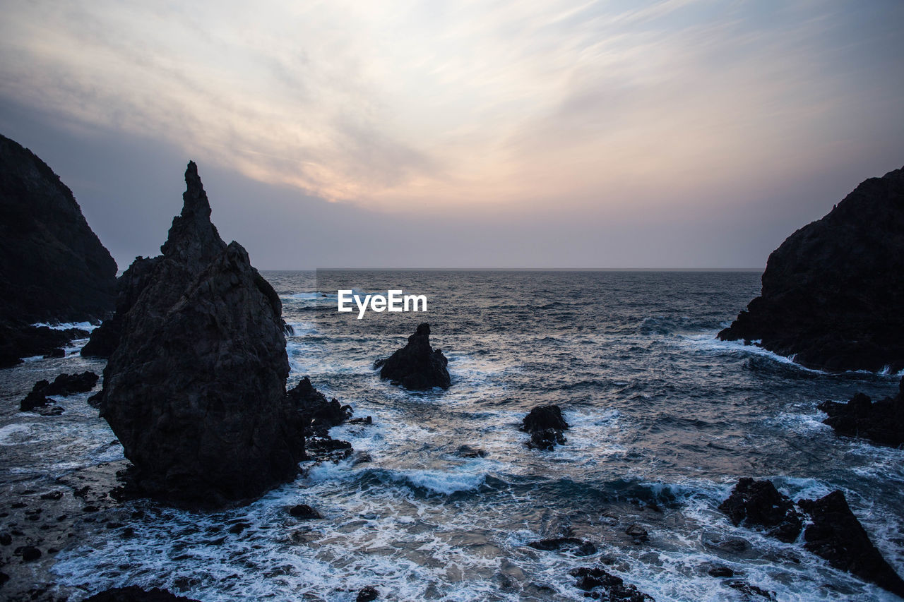 Rock formation on sea against sky during sunset