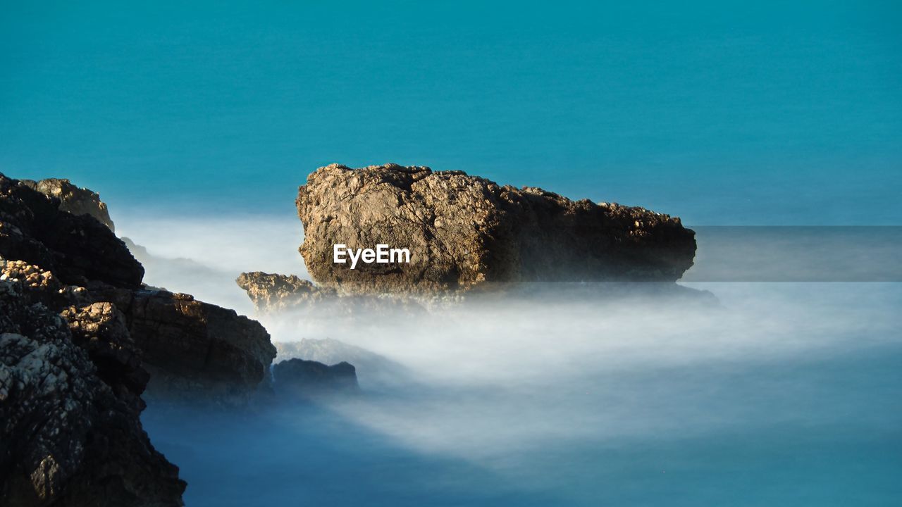 Rock formation in sea against blue sky