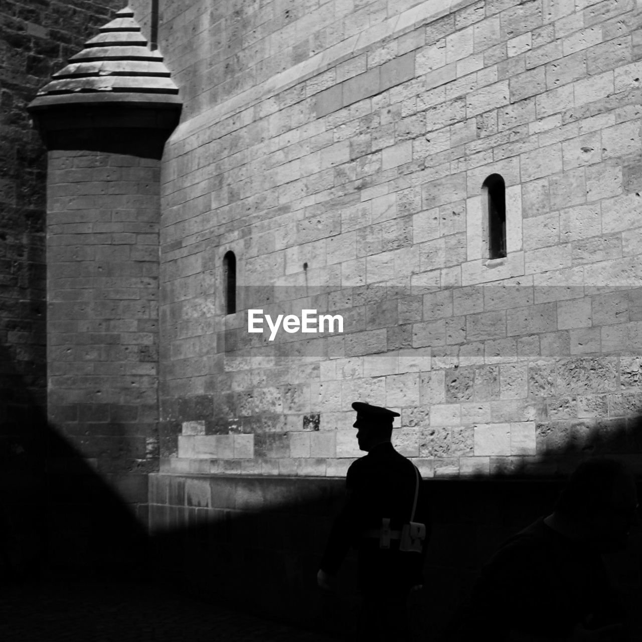 View of policeman against sun lighted wall 