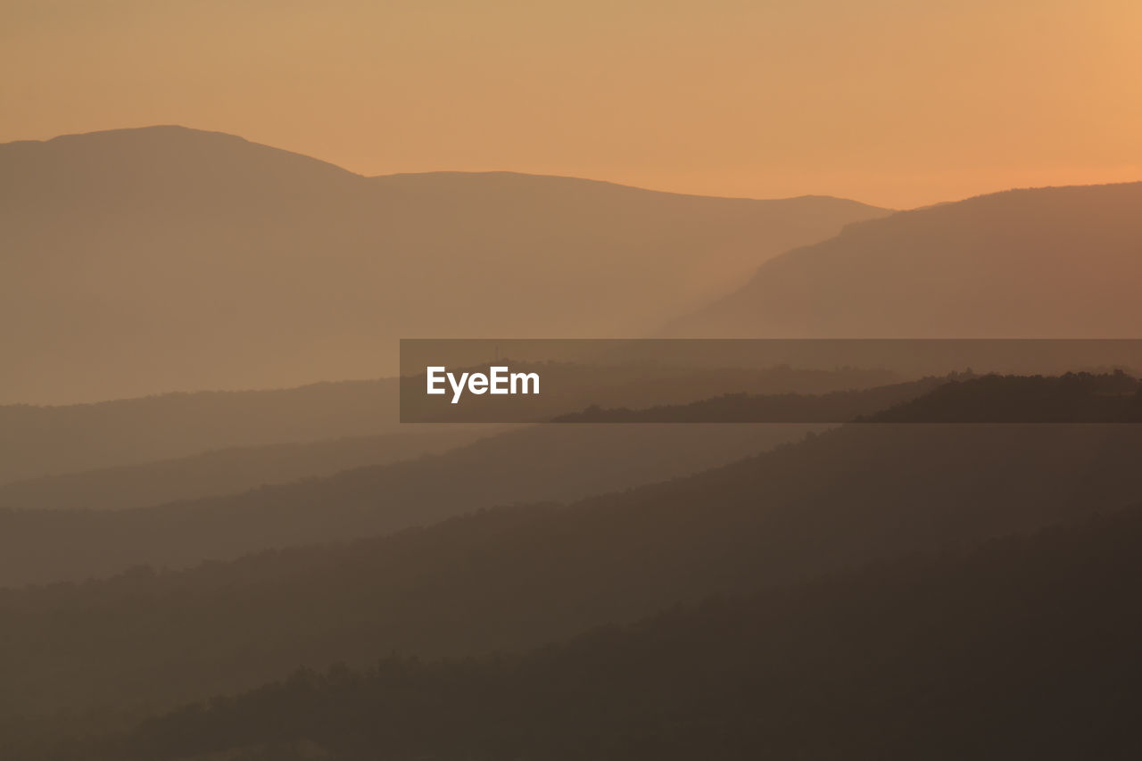 Silhouette landscape against mountains during foggy weather