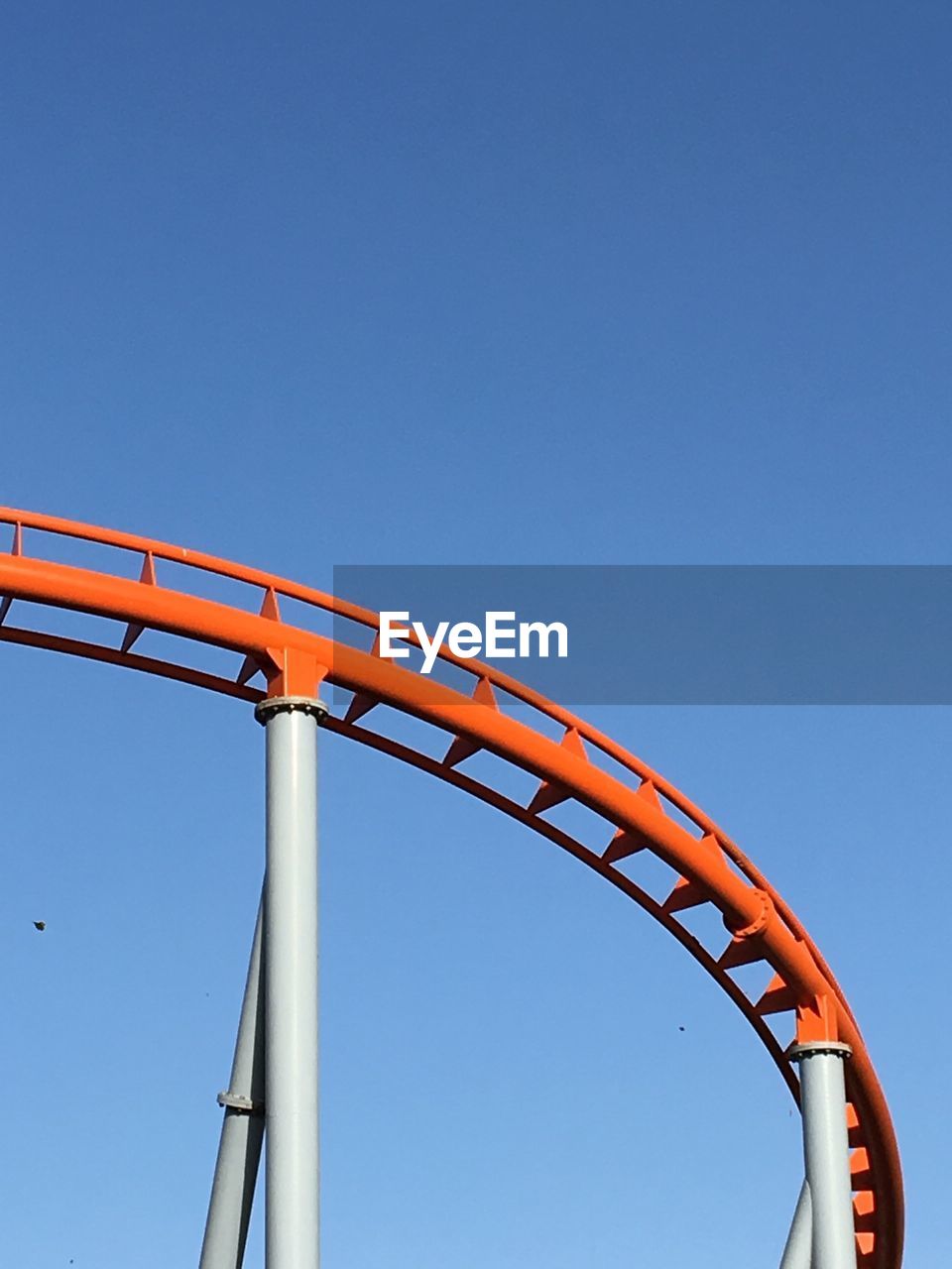 LOW ANGLE VIEW OF AMUSEMENT PARK AGAINST CLEAR BLUE SKY