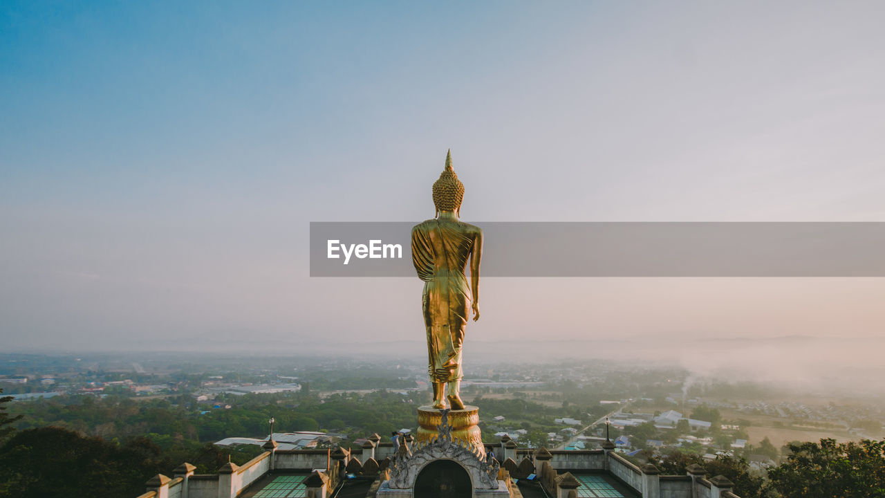 The buddha statue is on the top of a high hill.